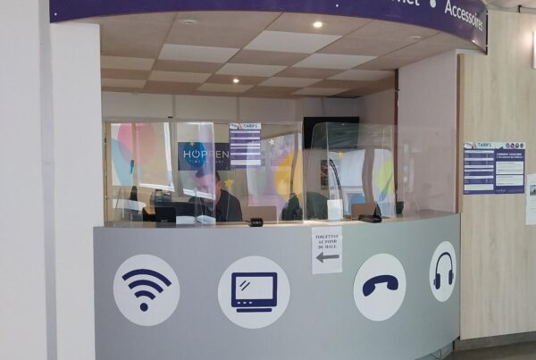 Photo d'un kiosk patientèle d'Hoppen a l'hôpital, indiquant l'offre de divertissement (wifi, TV et cast, téléphonie, musique, accessoires etc) en complément du centre d'appel patient